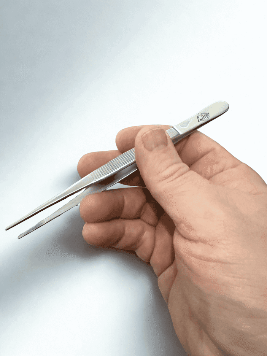Hand holding stainless steel tweezers